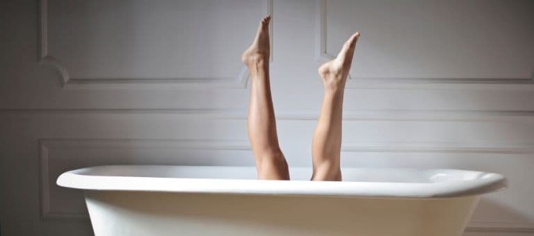 Minimal bir banyo küvetinde ayaklarını havaya kaldırmış bir kadın