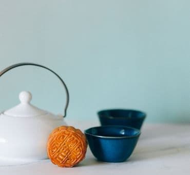 Beyaz bir demlik ve mavi seramik çay fincanları